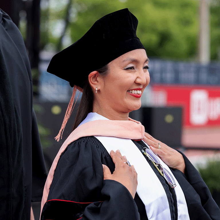 A female graduate smiles during her doctoral hooding