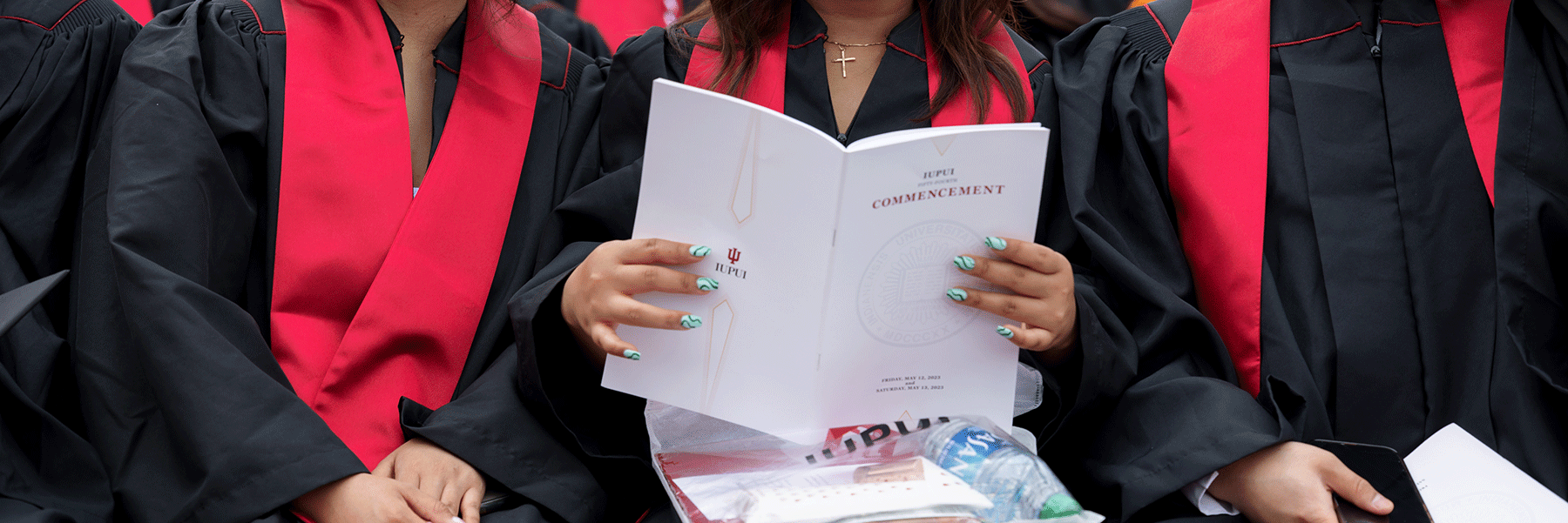 A graduate holds open a commencement program during the ceremony.