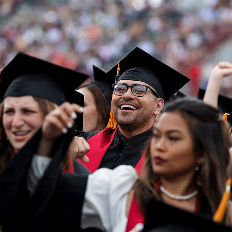 A male graduate smiles in the crowd during Commencement