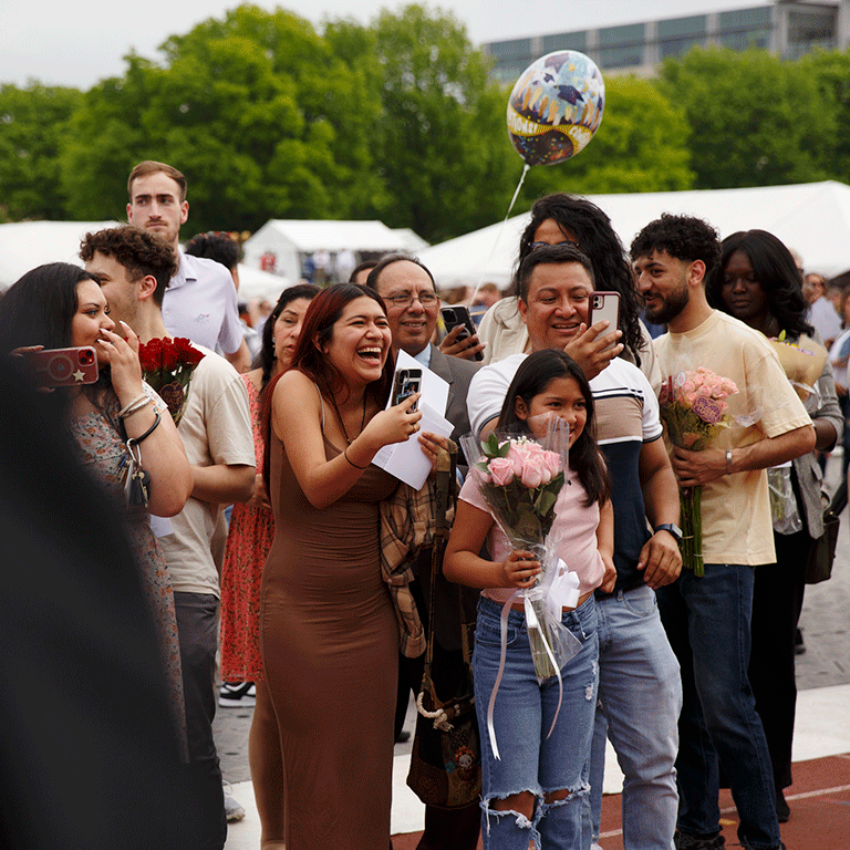 A family smiles and takes pictures with their cellphone after the commencement ceremony.