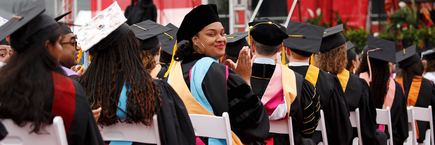 A seated female graduate looks back at the camera at the commencement ceremony.