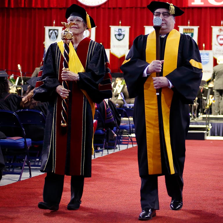 Purdue and IU grand marshals walk down the red carpet away from the Commencement stage