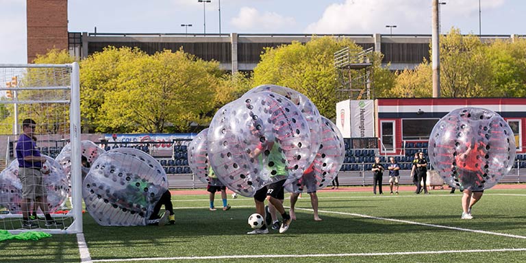 Students in inflatable balls around their torsos play a game of soccer.