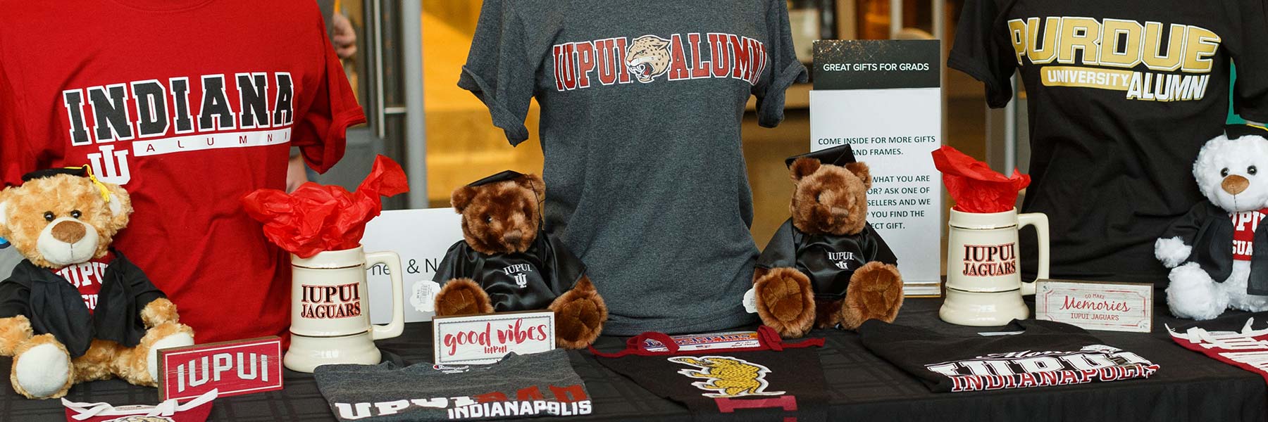 Tabletop display of IU and Purdue shirts, mugs, stuffed animals and other memorabilia items.
