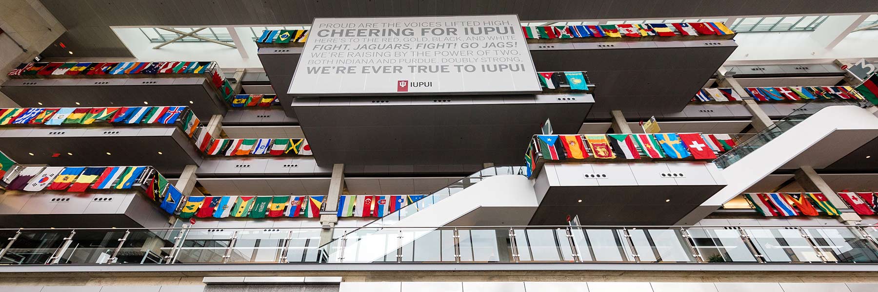 International flags hanging from the upper level floors as seen from the ground floor of the Campus Center atrium