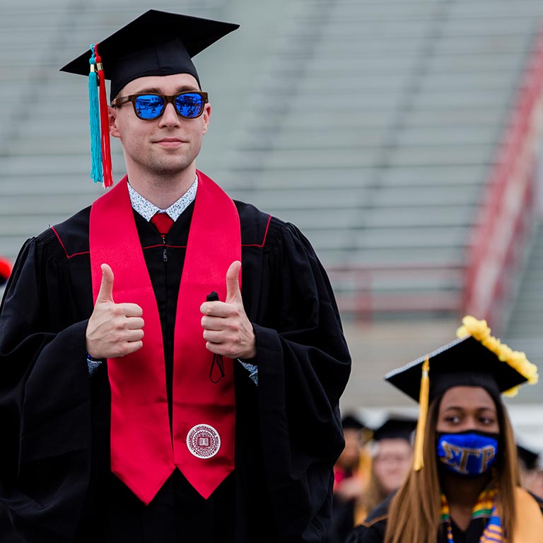 Graduate in sunglasses giving two thumbs up